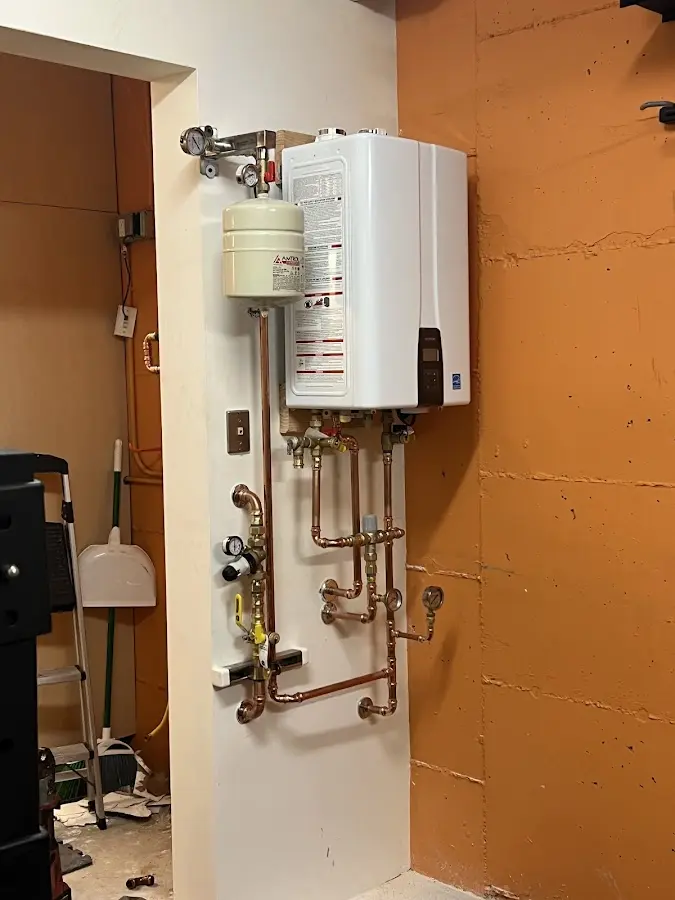 Plumbing technician inspecting water heater connections in Sterling